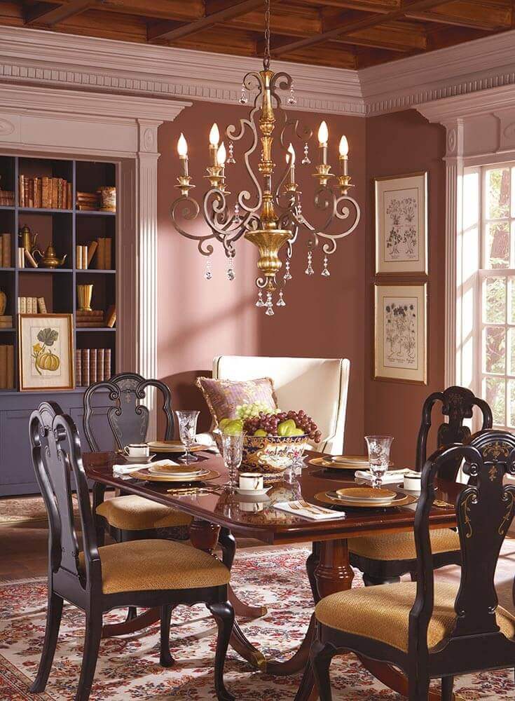 Lustre suspendu au-dessus d'une table de salle à manger, intérieur coloré avec bibliothèque.