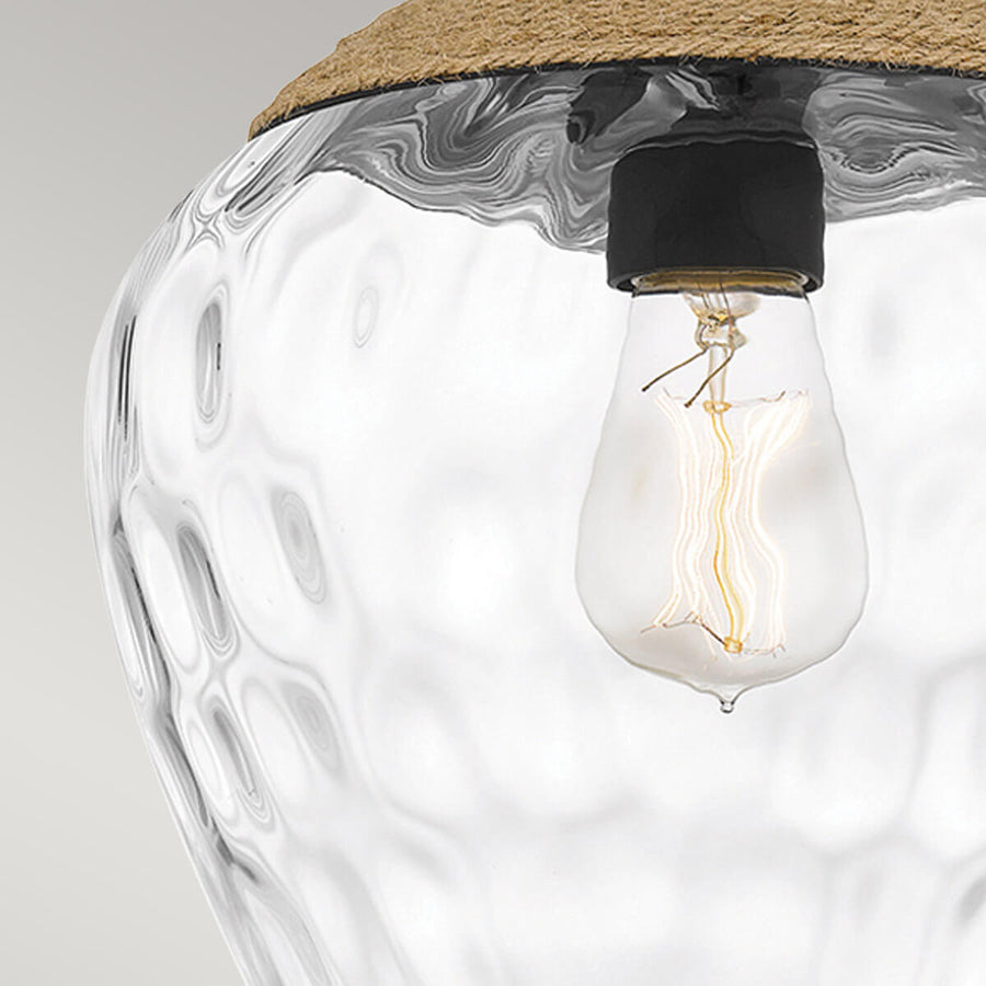 Macro de l'ampoule Edison allumée dans le verre martelé, reflets et transparence