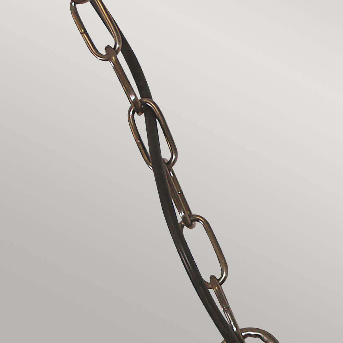 Détail de la chaîne métallique et du câble noir torsadé de la suspension.