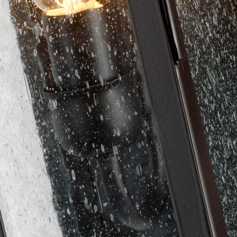 Vue rapprochée de l'ampoule allumée derrière le verre embué de pluie.