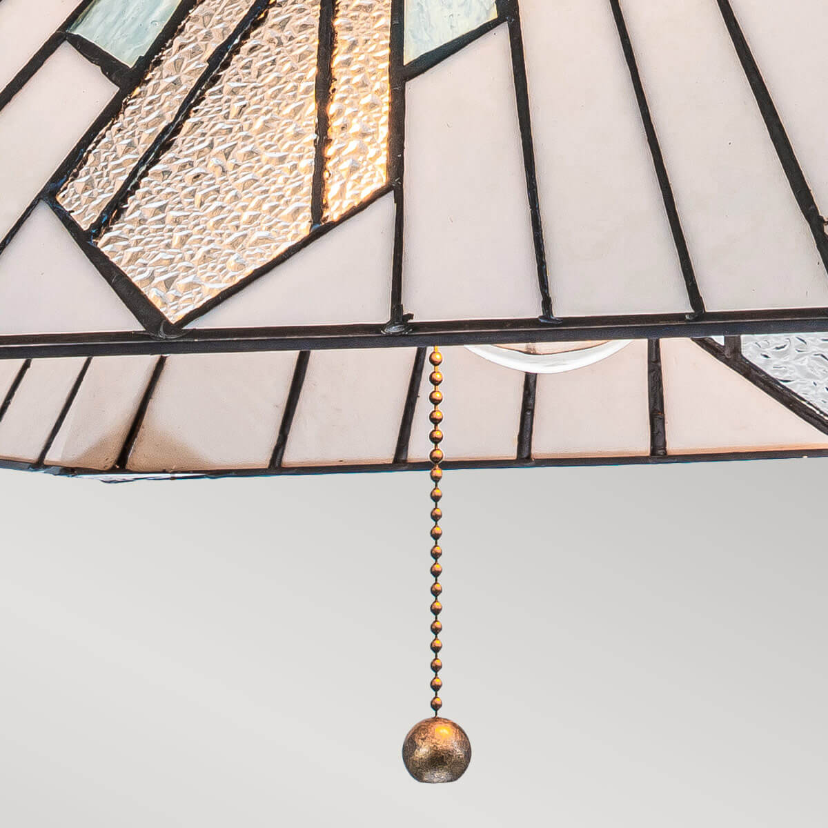 Détail du verre martelé éclairé et de la chaîne de tirage dorée