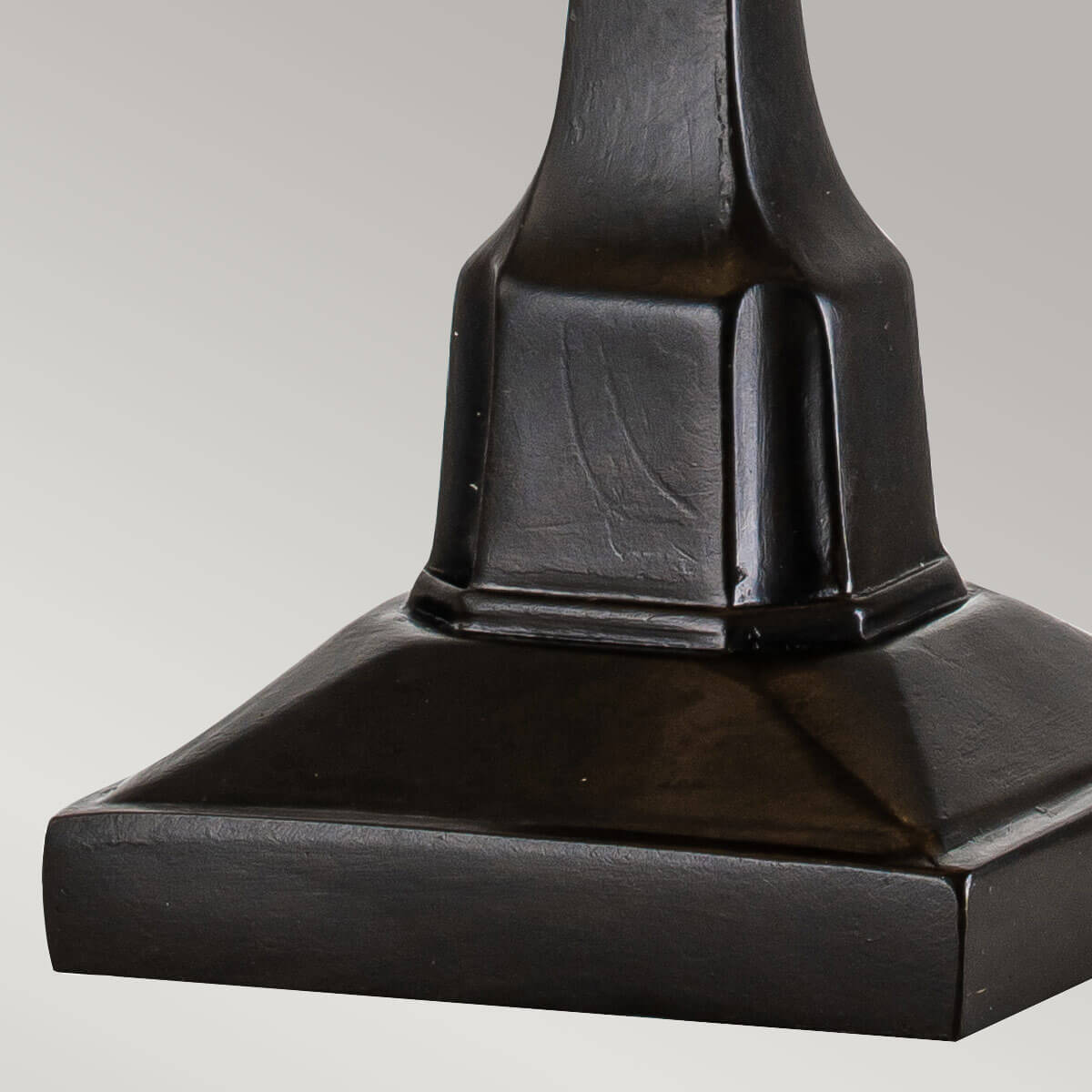 Détail de la base carrée moulée en métal à patine bronze sombre