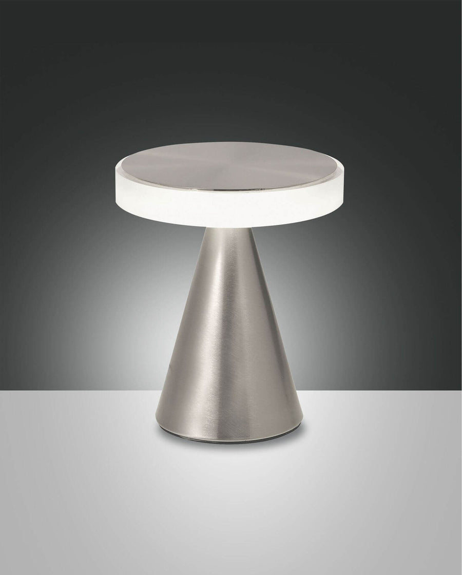 Lampe à poser chromée de face sur fond gris, base conique et diffuseur rond blanc