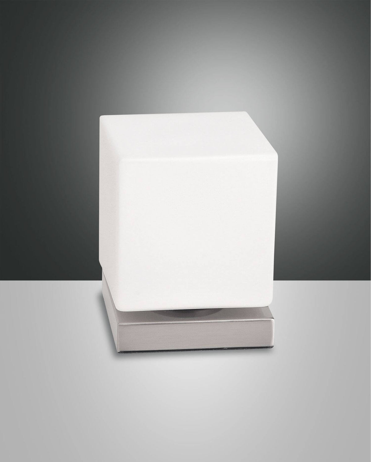 Lampe cube blanc opalin posée sur une base carrée chromée, fond gris studio