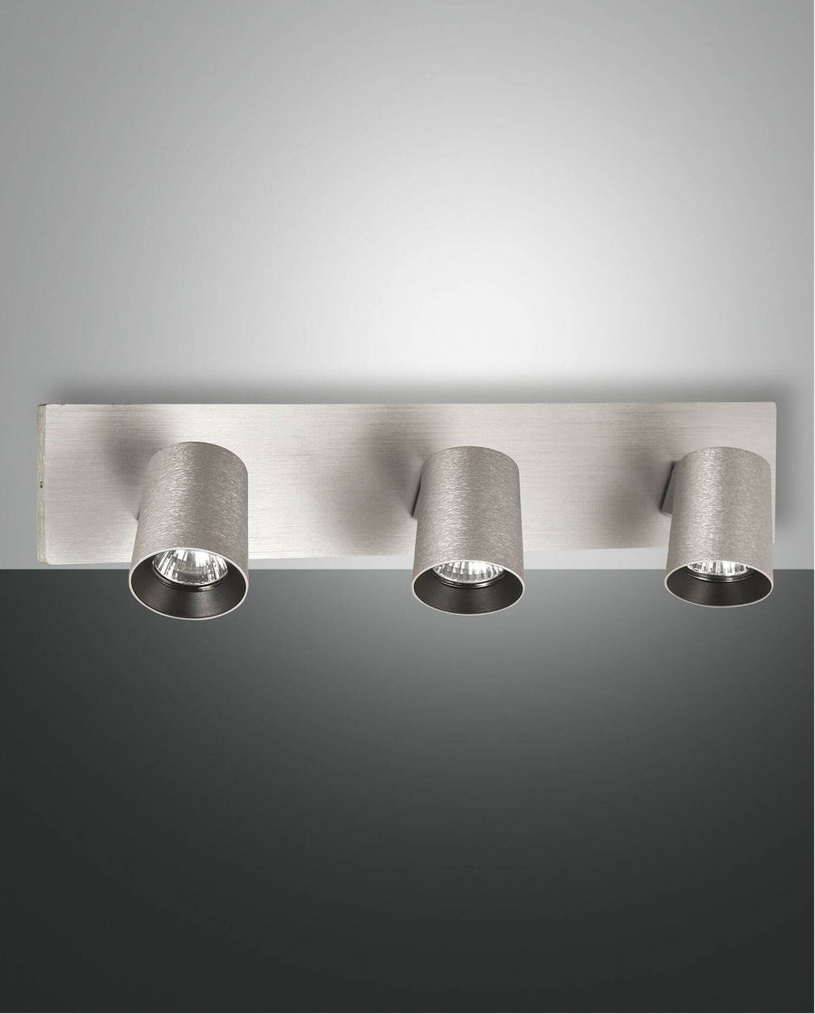 Vue de face du spot trois lumières en aluminium brossé avec projecteurs cylindriques orientables.