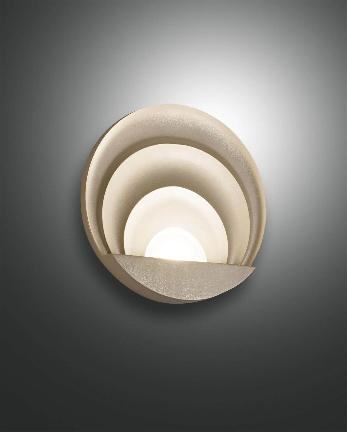Applique murale dorée vue de face, cercles concentriques et demi-lune diffusante sur fond gris