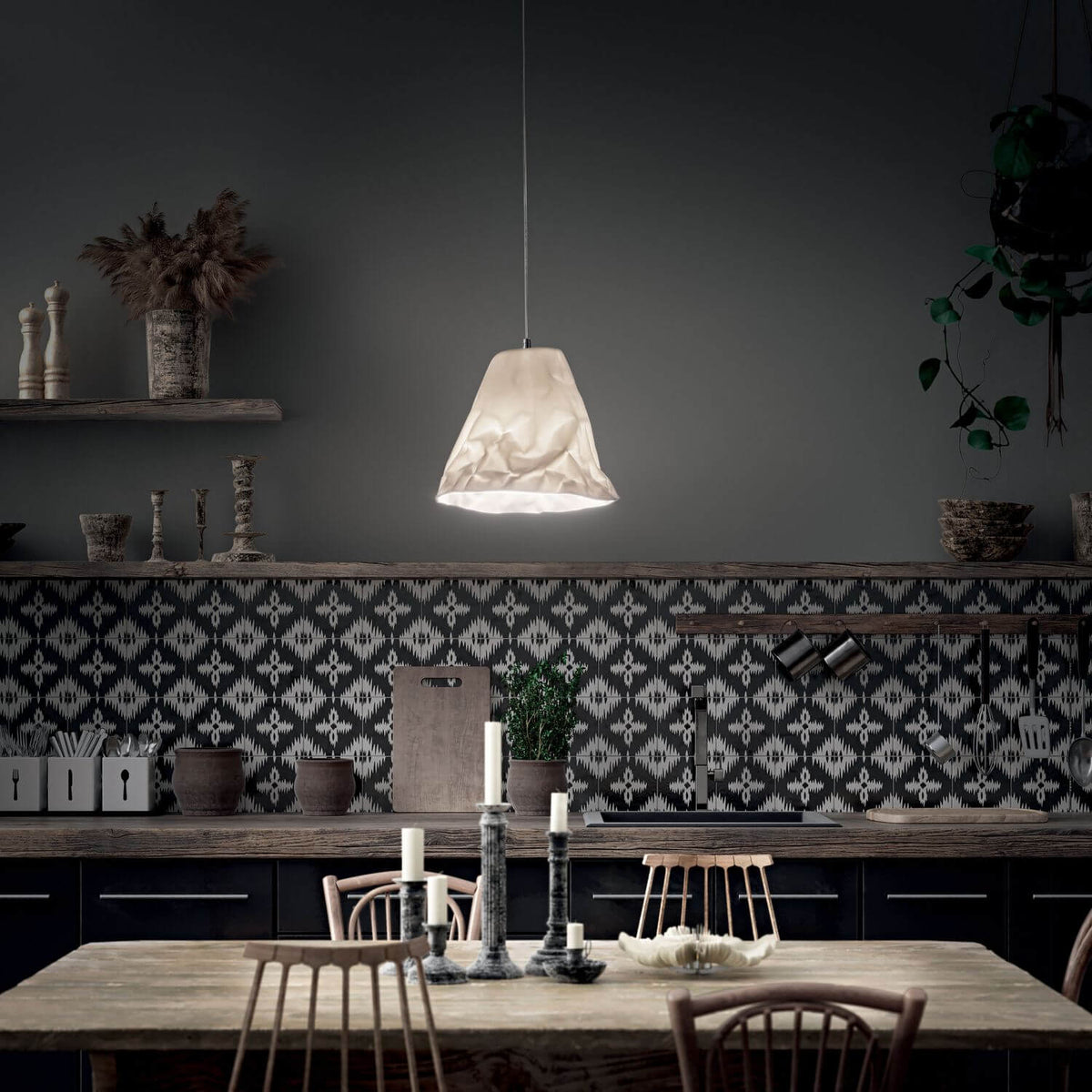 Mise en ambiance cuisine sombre, suspension allumée au-dessus d'une table rustique
