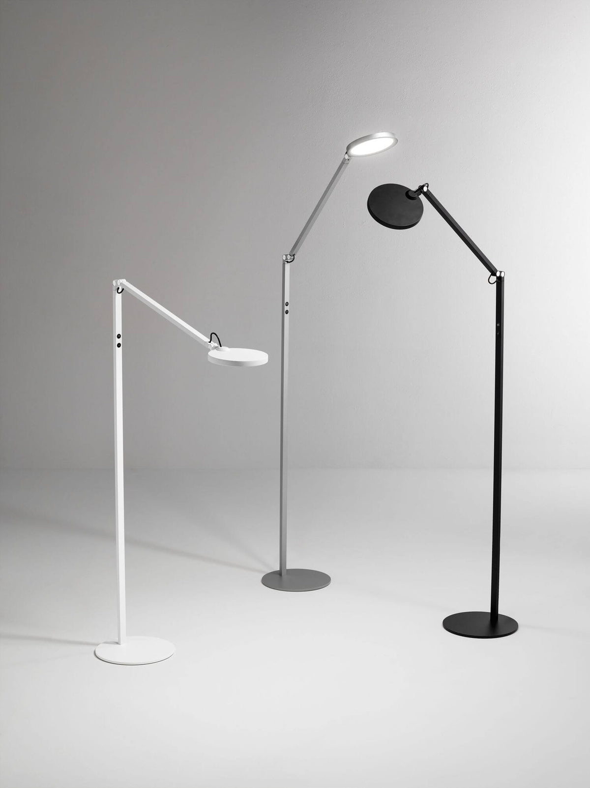 Trois lampes identiques déclinées en blanc, gris et noir, alignées sur fond clair