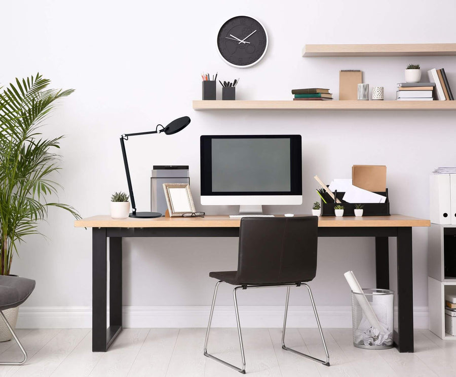 Lampe à poser noire installée sur un bureau en bois dans un intérieur lumineux.