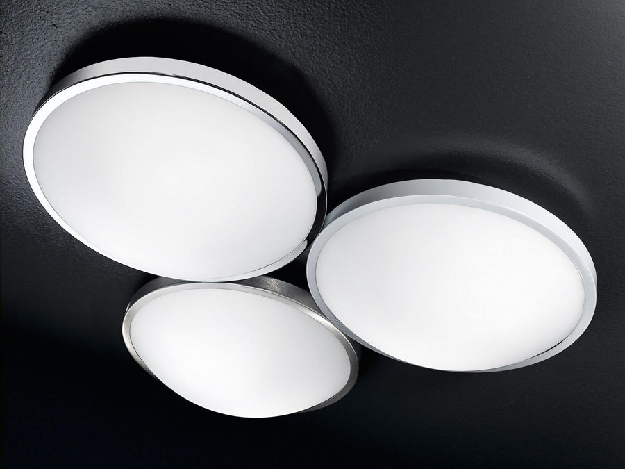 Trois plafonniers ronds lumineux fixés au plafond noir texturé, vus en plongée