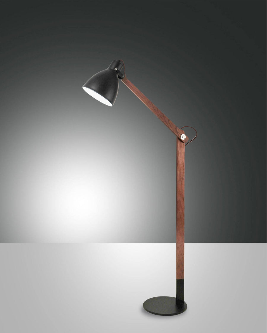Lampe sur fond gris dégradé, abat-jour noir et long bras en bois incliné.