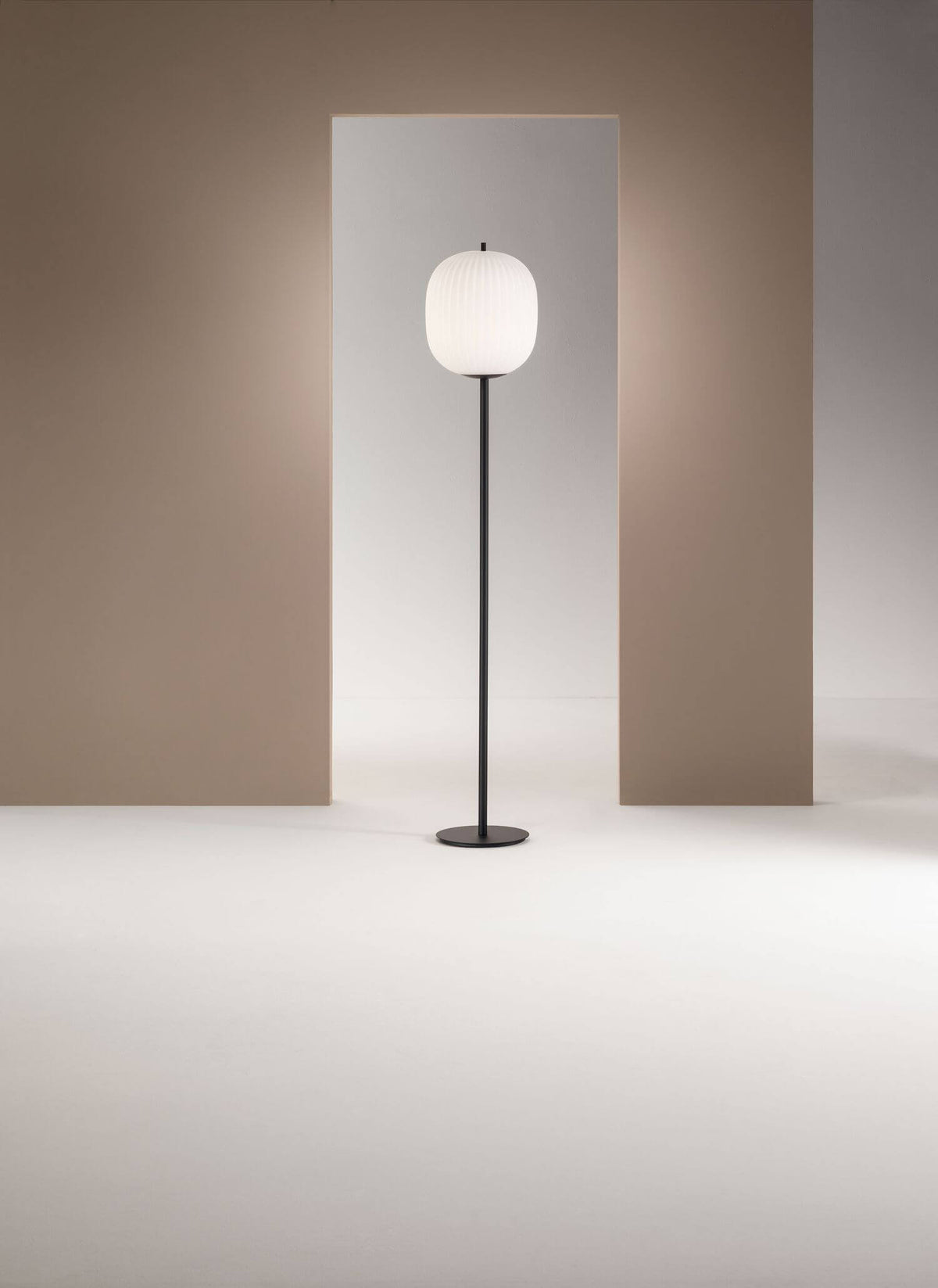 Mise en ambiance du lampadaire devant deux panneaux beige, lumière tamisée