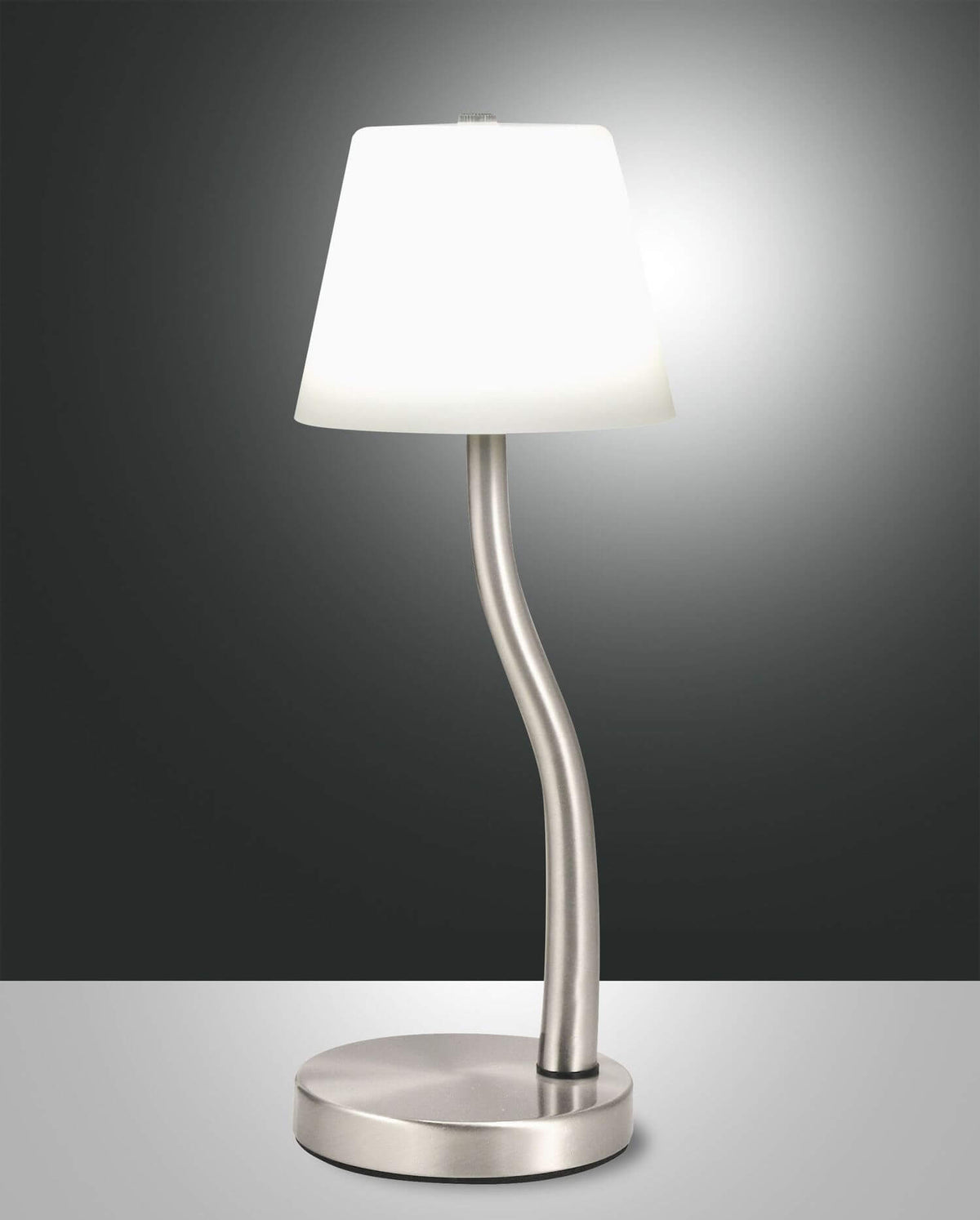 Lampe à poser chromée de face sur fond sombre, abat-jour blanc allumé