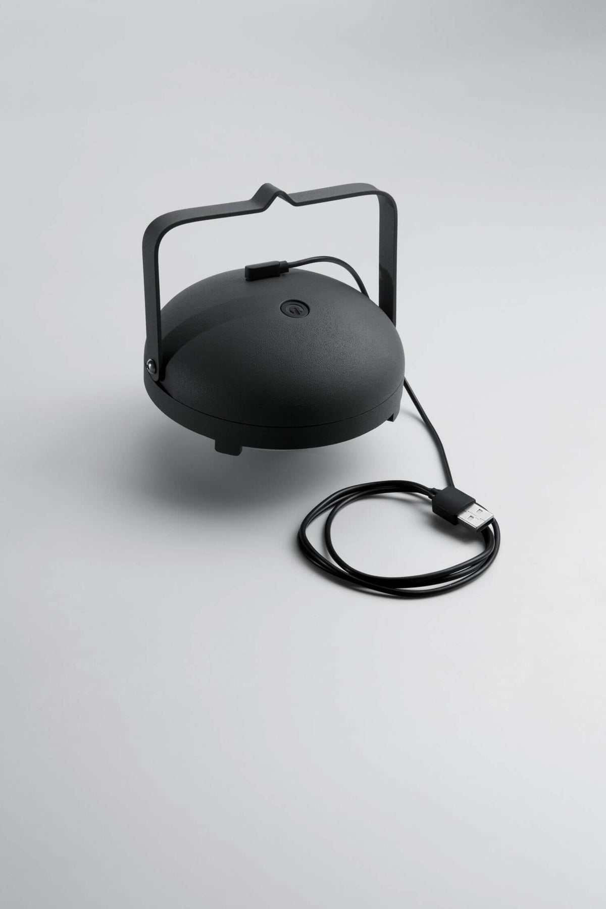 Module d'éclairage noir avec câble USB et connecteur, posé sur fond gris clair.