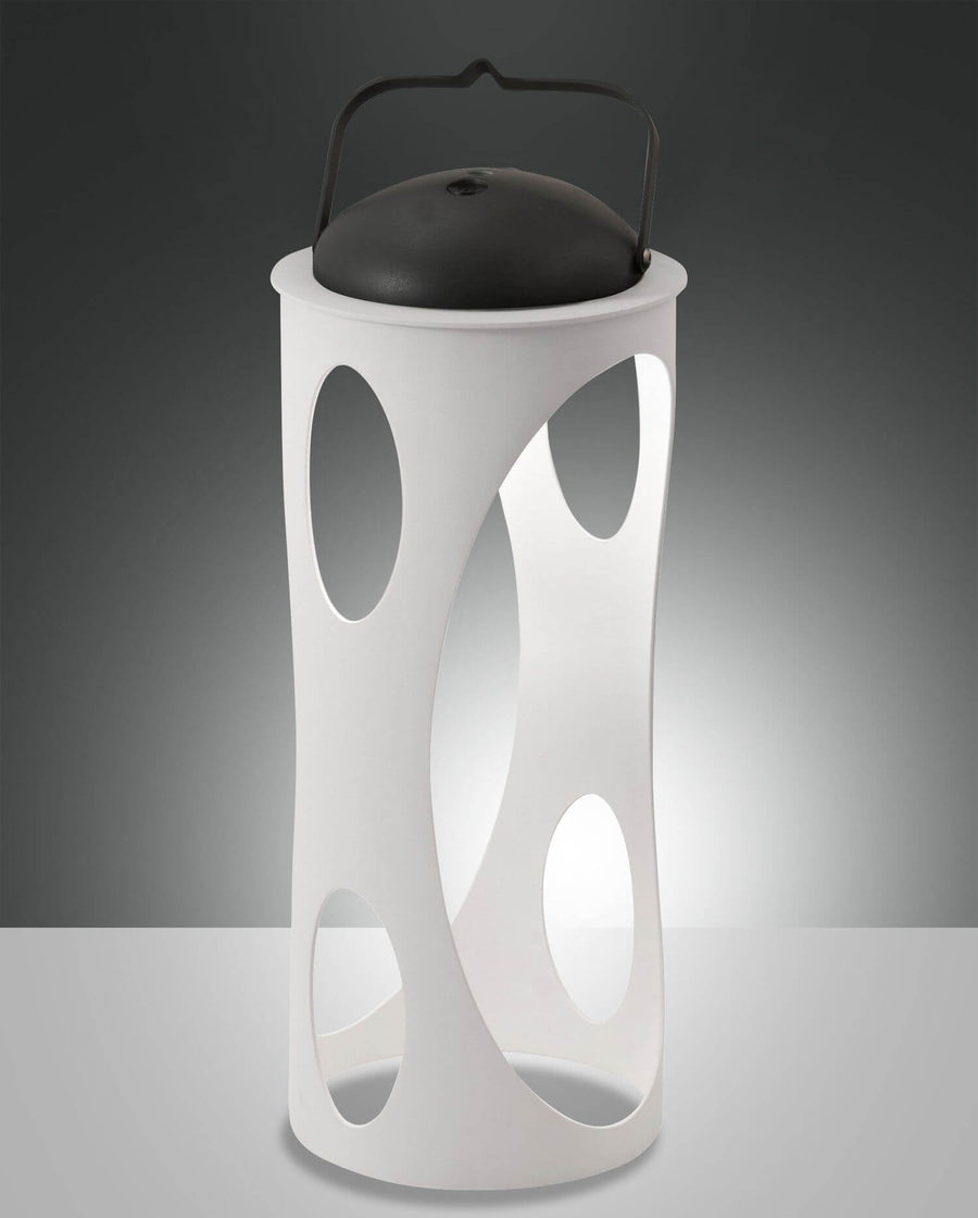 Lampe blanche ajourée de face, posée, avec anse et dôme noirs.