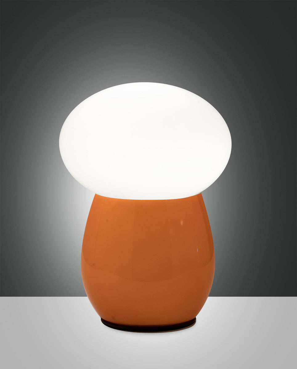 Lampe à poser ambrée allumée, vue de face sur fond gris dégradé