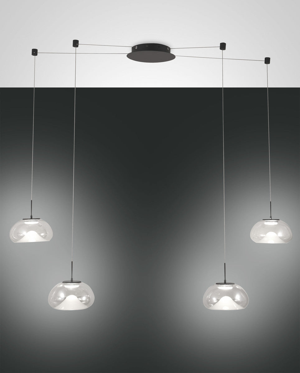 Quatre suspensions en verre transparent, câbles fins, sur fond gris dégradé.