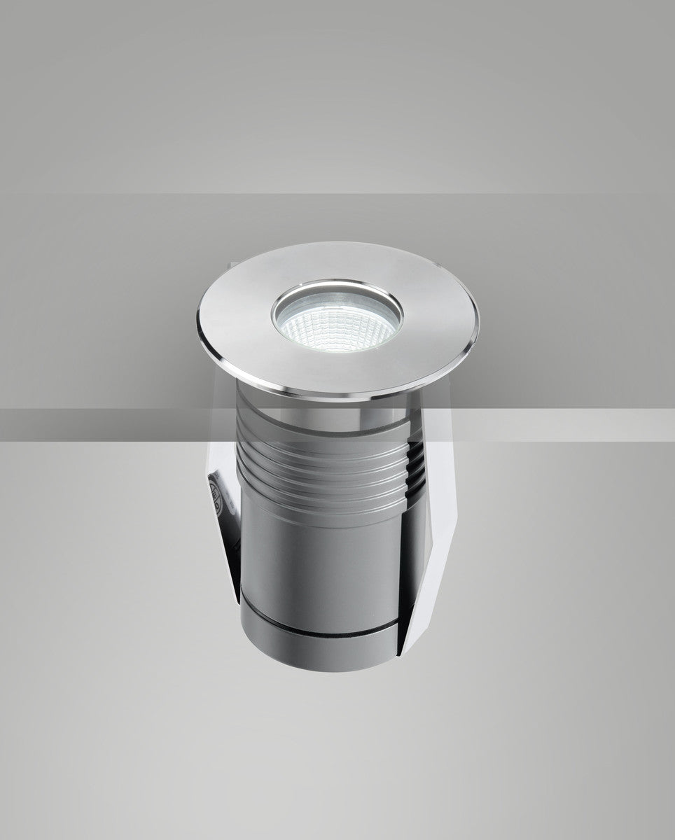 Vue plongeante du luminaire allumé, lentille LED et collerette ronde en acier poli