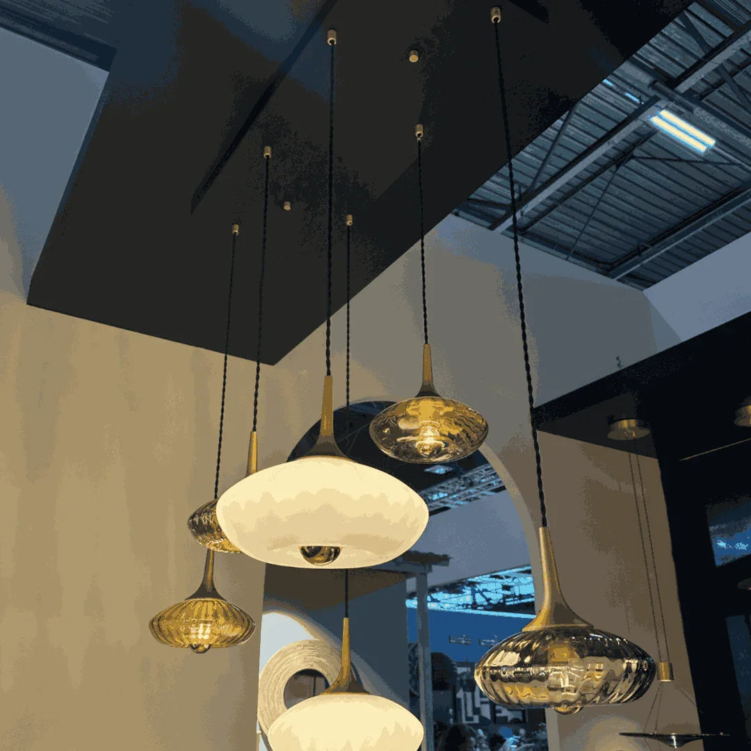 Luminaires suspendus en verre soufflé, ampoules allumées, plafond sombre et poutres apparentes
