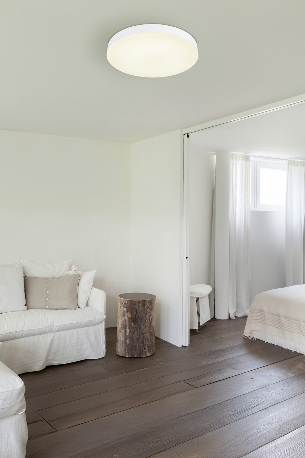 Mise en ambiance du plafonnier allumé dans un séjour aux murs blancs