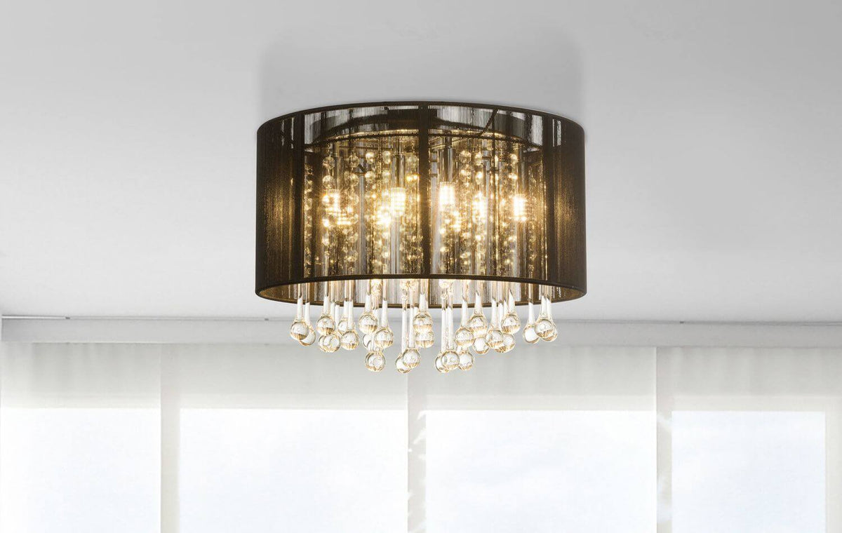 Plafonnier installé au plafond blanc, éclairé, montrant son contour cylindrique et ses cristaux scintillants en intérieur.
