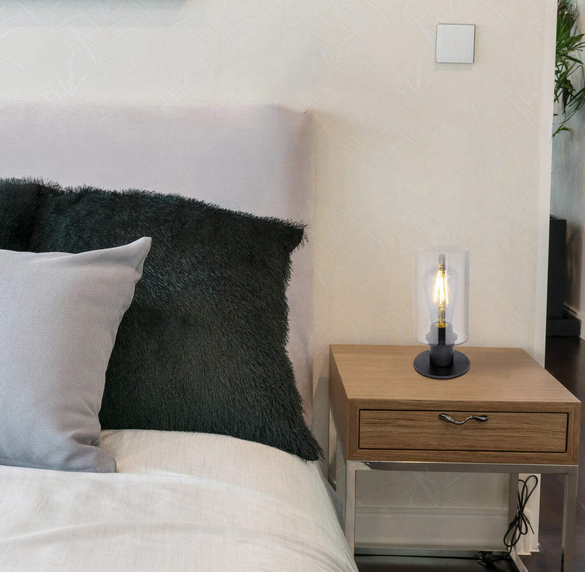 Mise en ambiance de la lampe posée sur une table de chevet en bois.