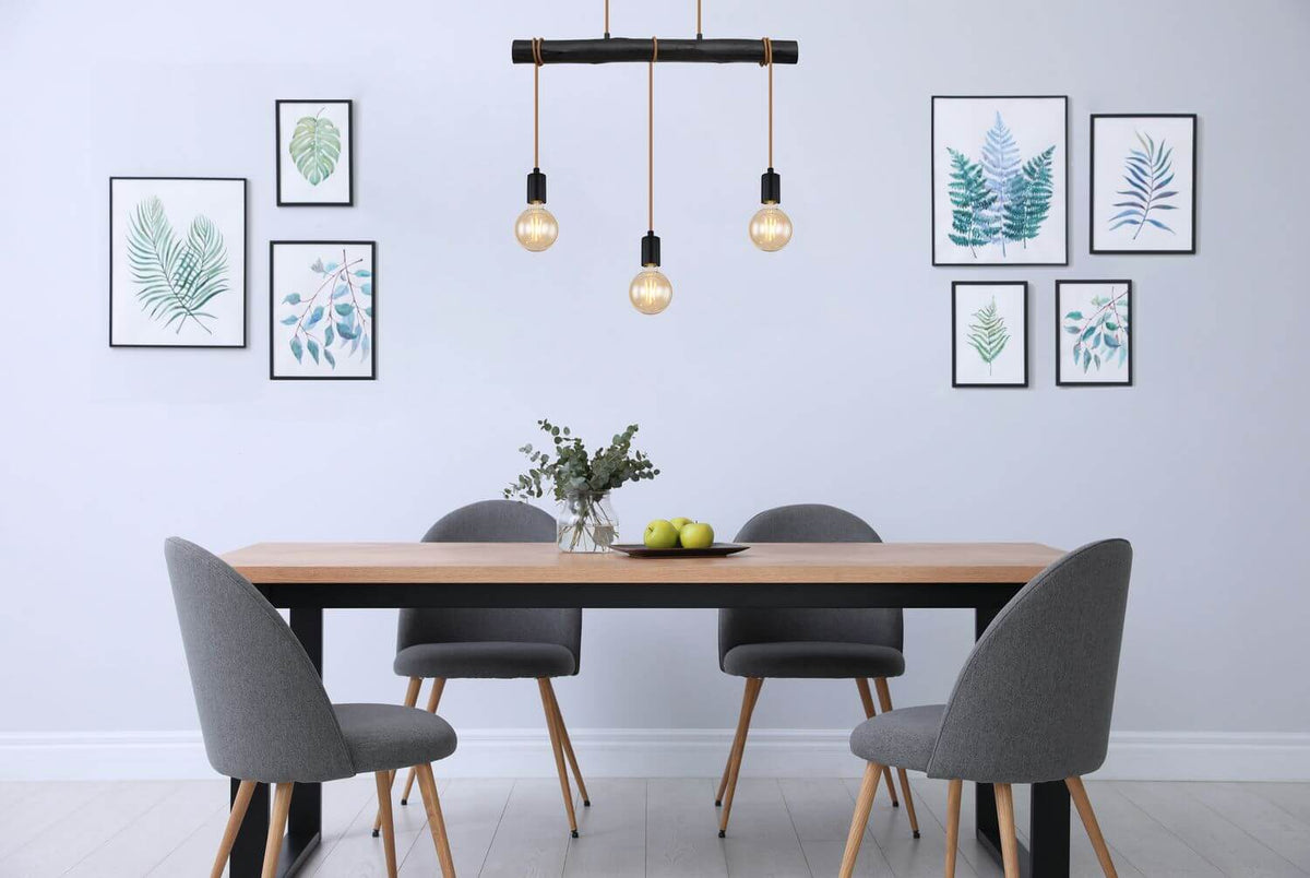 Mise en ambiance au-dessus d'une table à manger grise avec cadres de feuillages
