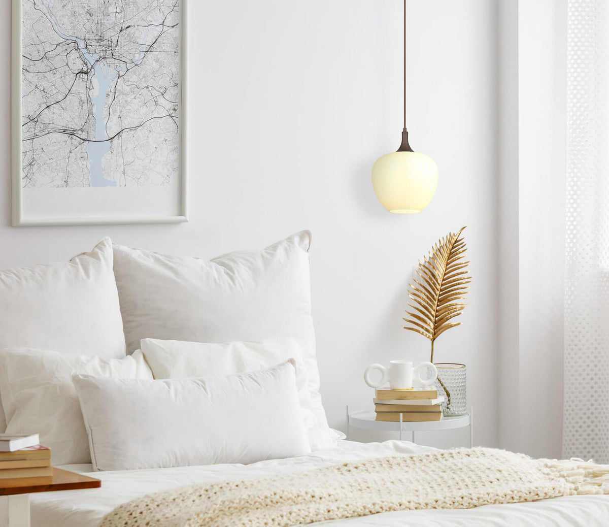 Mise en ambiance dans une chambre blanche, suspension allumée au-dessus de la table de chevet