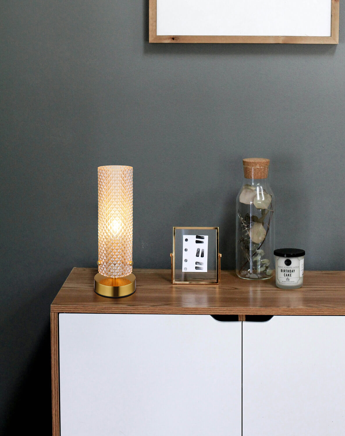 Mise en ambiance sur un meuble en bois auprès d'un vase et d'une bougie