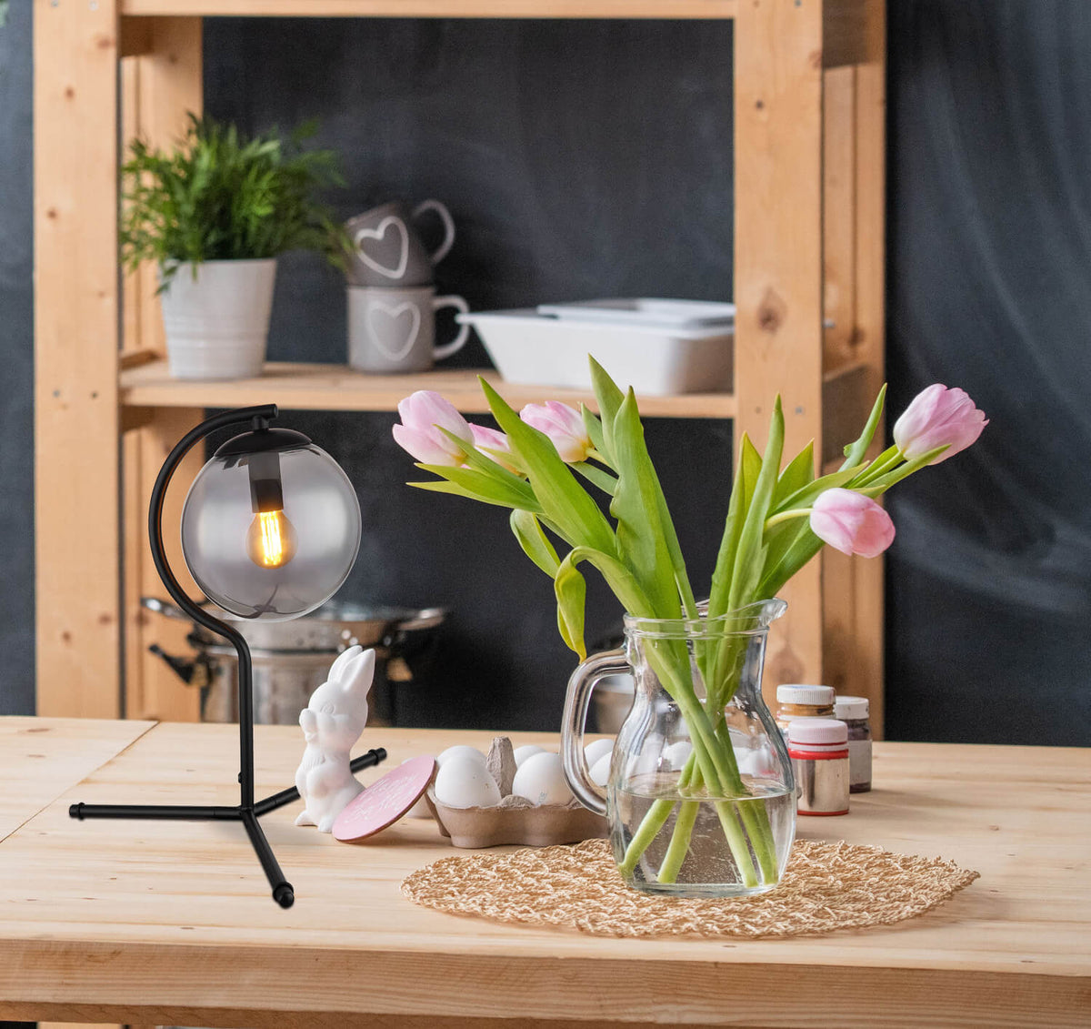 Mise en ambiance sur table en bois avec lampe allumée et tulipes