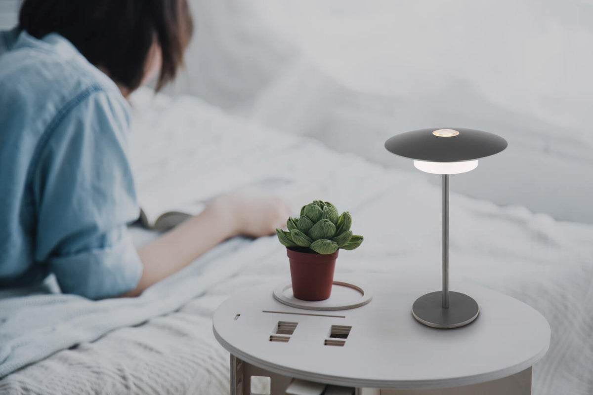 Mise en ambiance sur une table de chevet, personne lisant près d'une plante