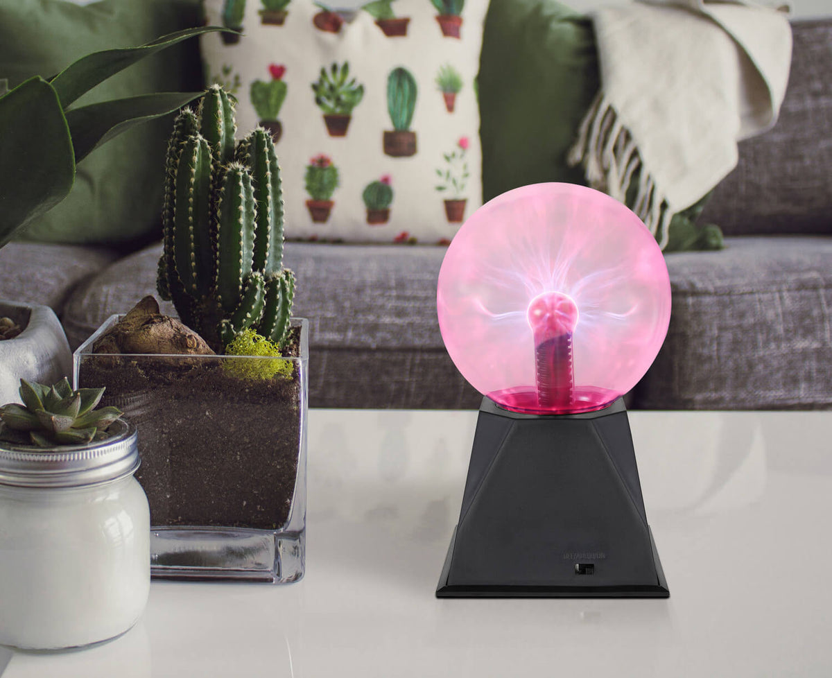 Mise en ambiance sur table basse avec cactus et coussins, plasma rose allumé