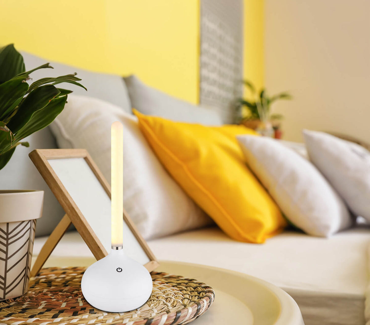 Mise en ambiance sur table basse, canapé jaune et coussins dans un salon
