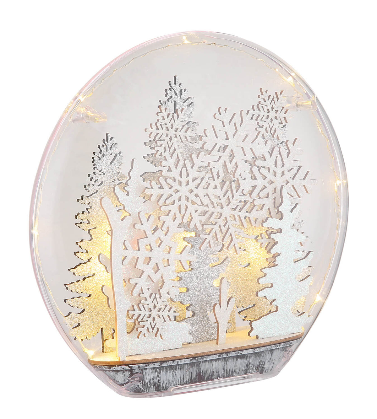Lampe à poser transparente de face, éclairée, montrant des sapins et flocons en découpe laser.