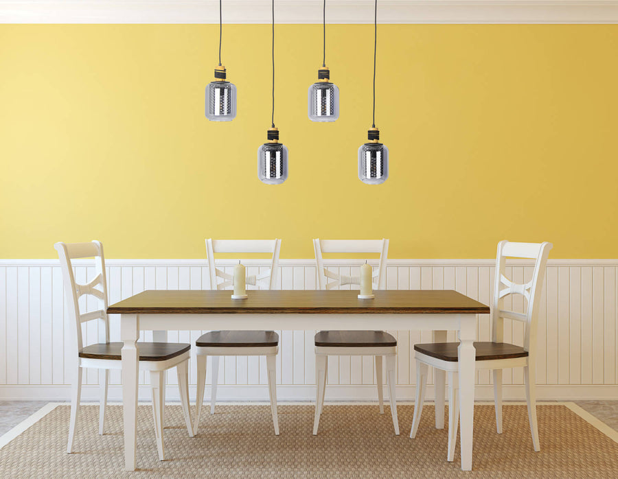 Suspension suspendue au-dessus d'une table à manger devant un mur jaune et des chaises blanches.