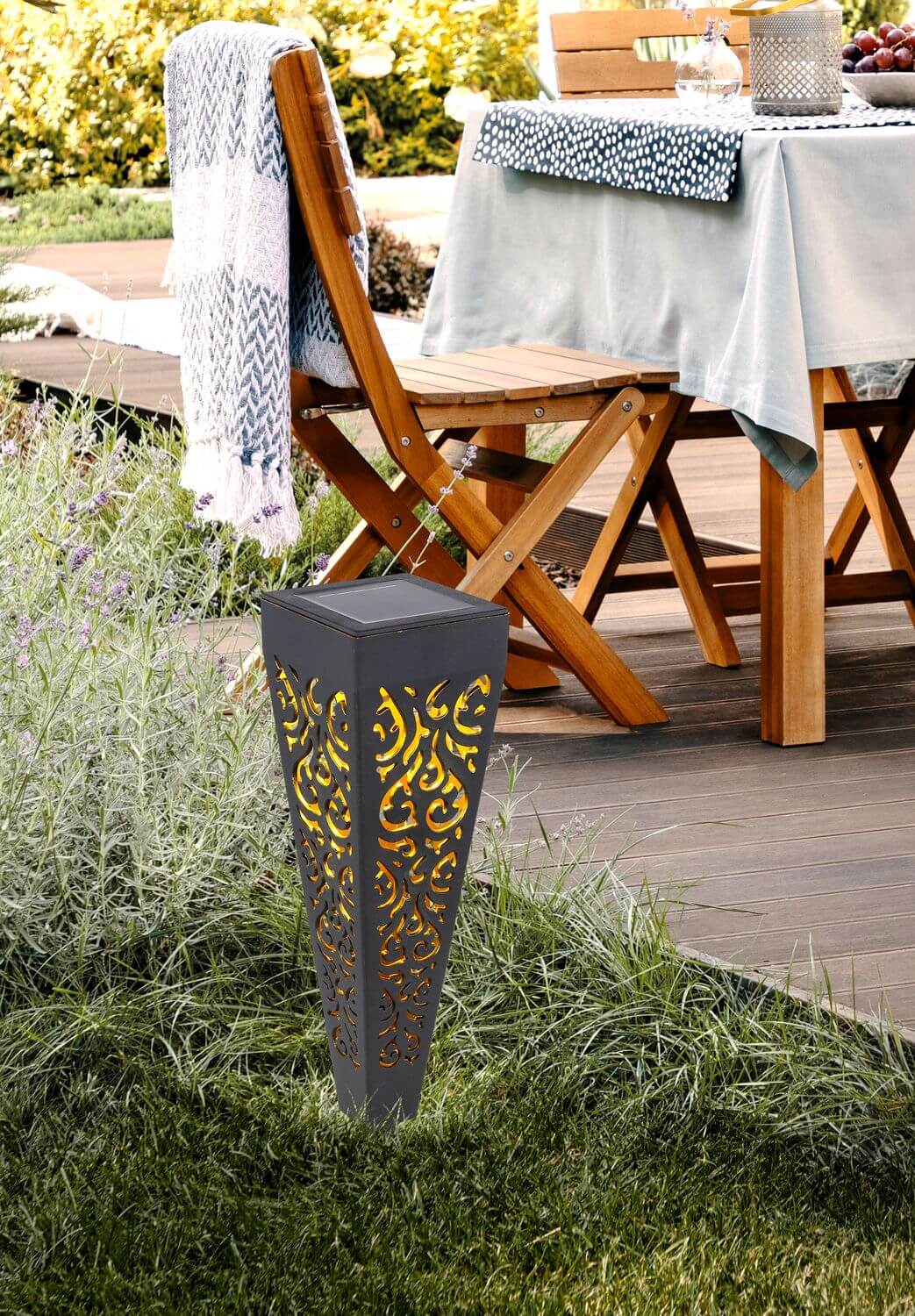 Mise en ambiance, le luminaire planté dans la pelouse près d'une table de jardin