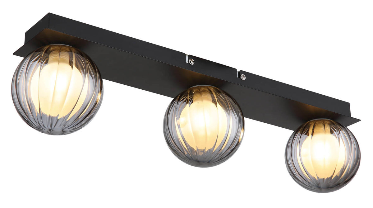 Détail du plafonnier avec ses trois globes en verre cannelé et sa base rectangulaire noire.