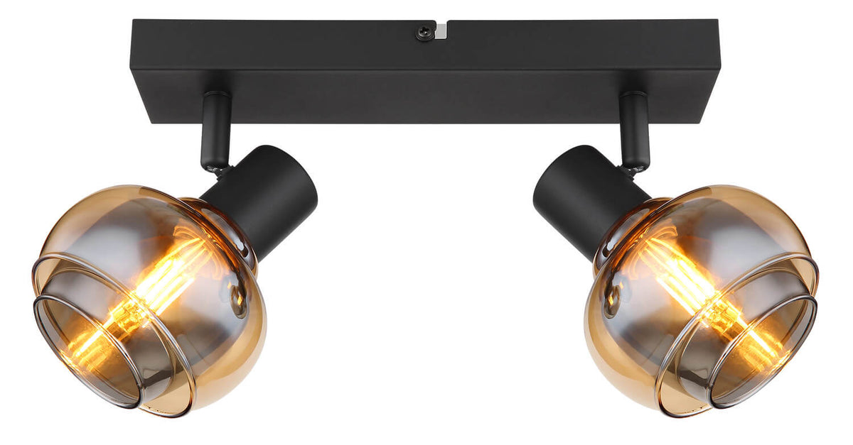 Gros plan du luminaire allumé, cadrant les deux verres ambrés et la base noire.
