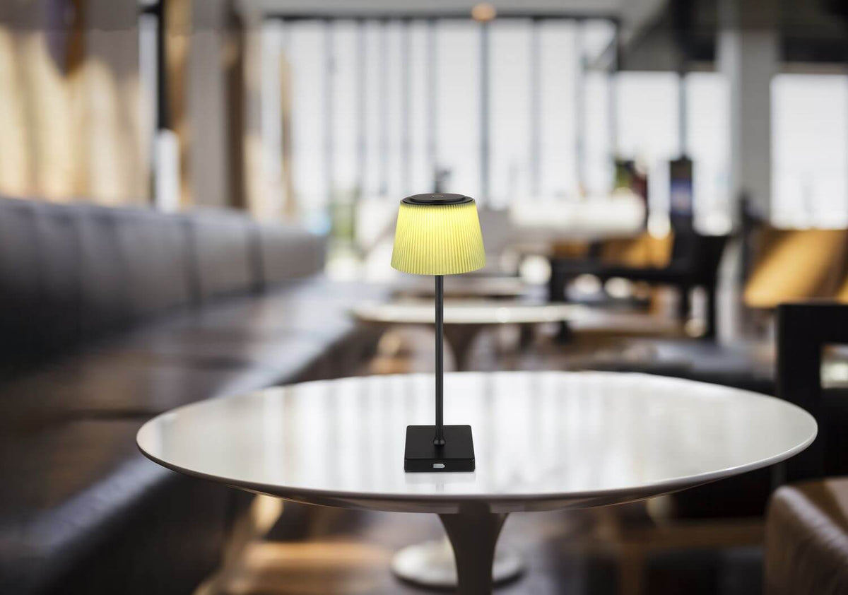 Lampe jaune posée sur une table ronde dans un salon de restaurant flou
