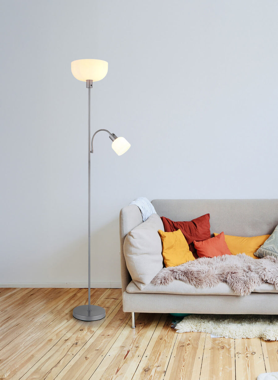Lampadaire argenté installé près d'un canapé dans un intérieur clair avec parquet.