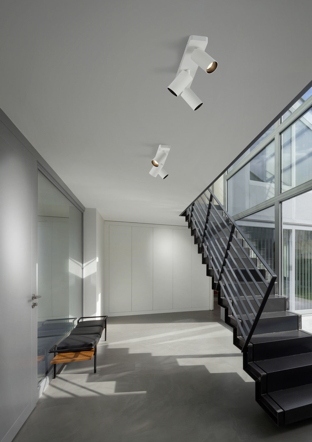Mise en ambiance dans un hall avec escalier, spots blancs orientables fixés au plafond