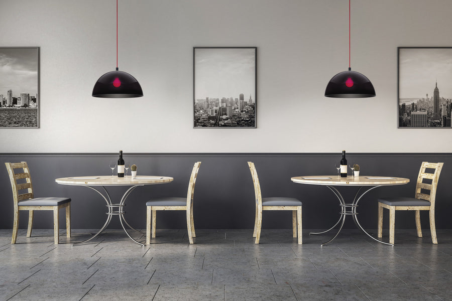 Deux suspensions noires au-dessus de tables de restaurant, intérieur rouge et décor urbain.