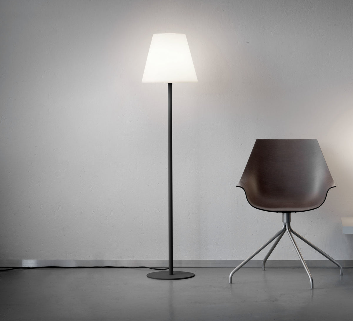 Mise en ambiance intérieure avec fauteuil design sombre, lumière diffusée vers le haut