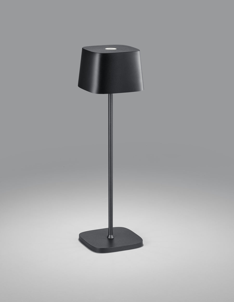Lampe noire de face, abat-jour tronconique, tige fine et socle carré posé au sol