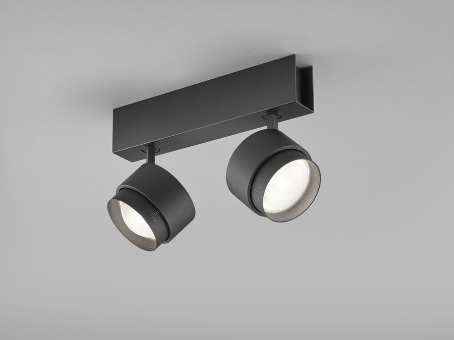Vue de face du plafonnier noir, deux spots cylindriques orientables sous une embase rectangulaire.