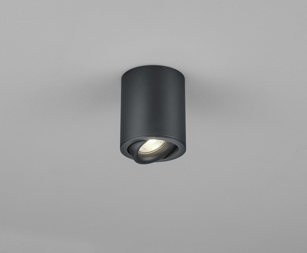 Vue de face d'un plafonnier cylindrique noir orientable, avec ampoule allumée