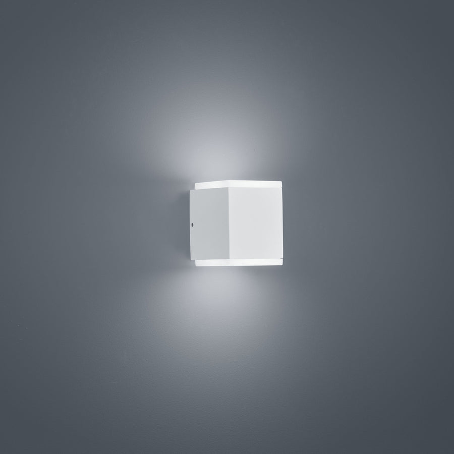 Vue de trois quarts du luminaire blanc, montrant la platine de fixation murale et sa forme carrée.