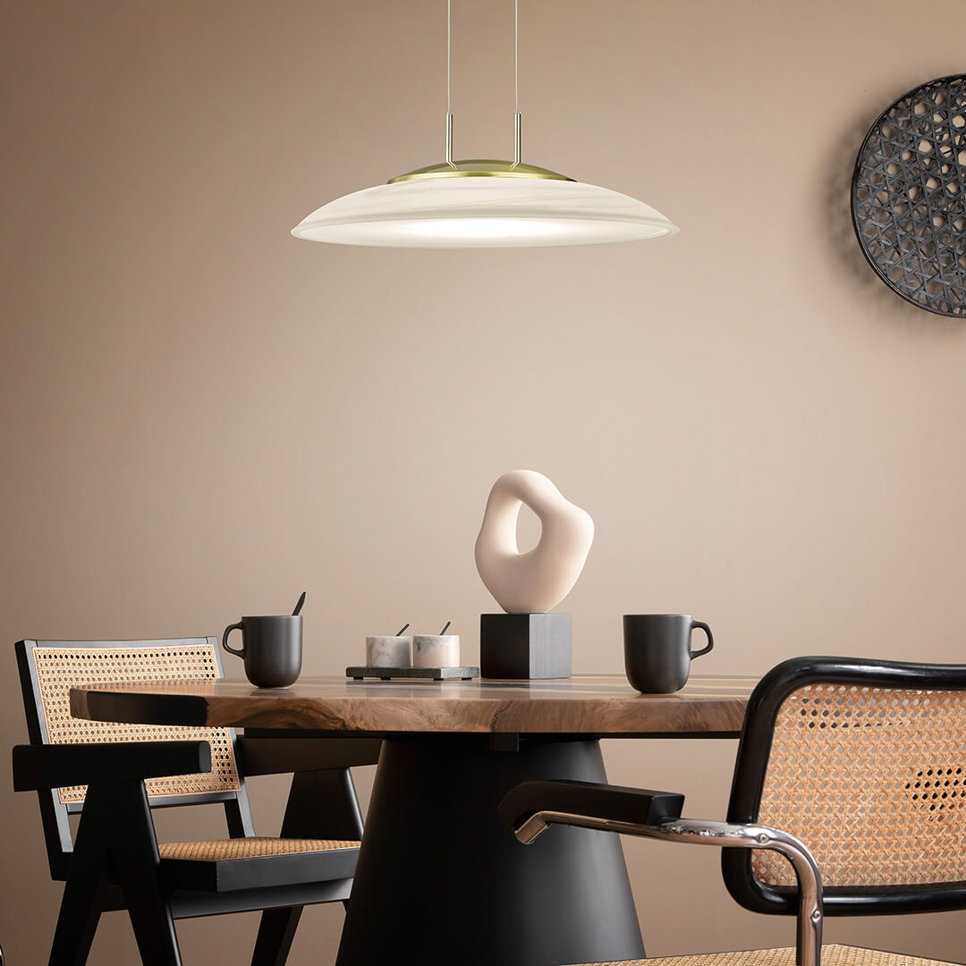 Mise en ambiance au-dessus d'une table à manger en bois, avec chaises cannées et décor mural.