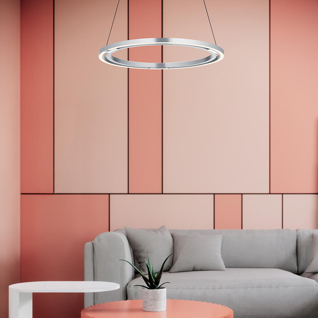 Mise en ambiance du luminaire suspendu devant un mur rose et un canapé gris