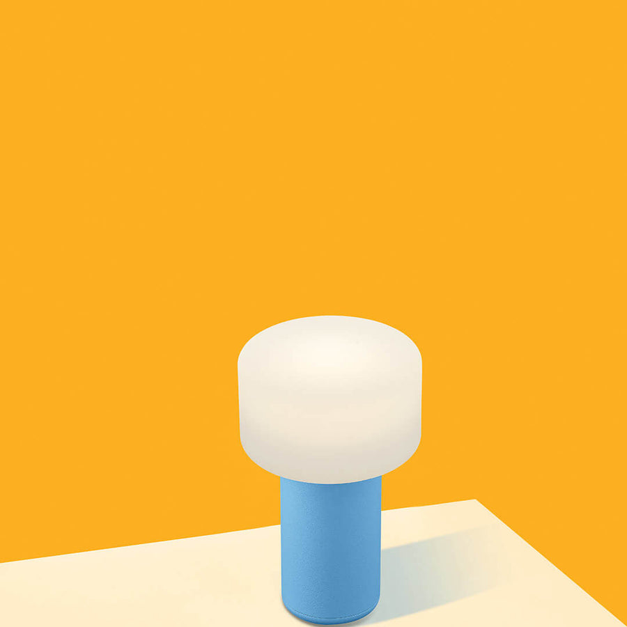 Lampe sans fil bleue et blanche posée sur une table, fond jaune vif